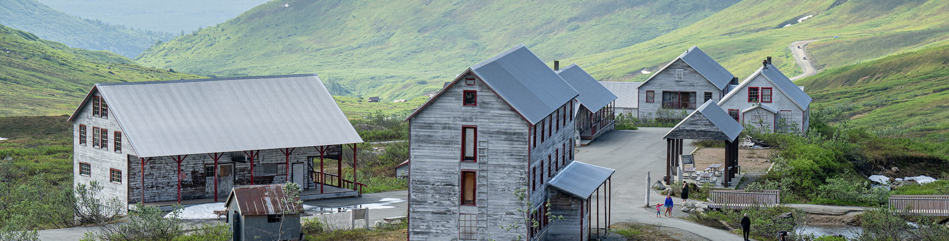 The historic Independence Mine buildings at Hatcher Pass, weathered wood structures set against green Alaskan mountainsides